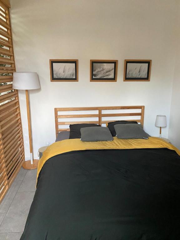 - un lit dans une chambre avec 3 photos sur le mur dans l'établissement LES GITES CHEROIS, ravissant cottage, 3 personnes, à Les Chères