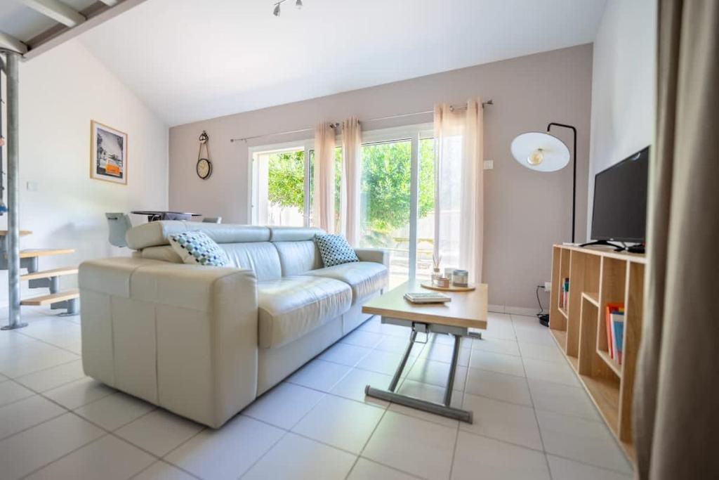 un salon avec un canapé blanc et une table dans l'établissement Appartement L'écrin de Lumière - Résidence Kiwi, à Aytré