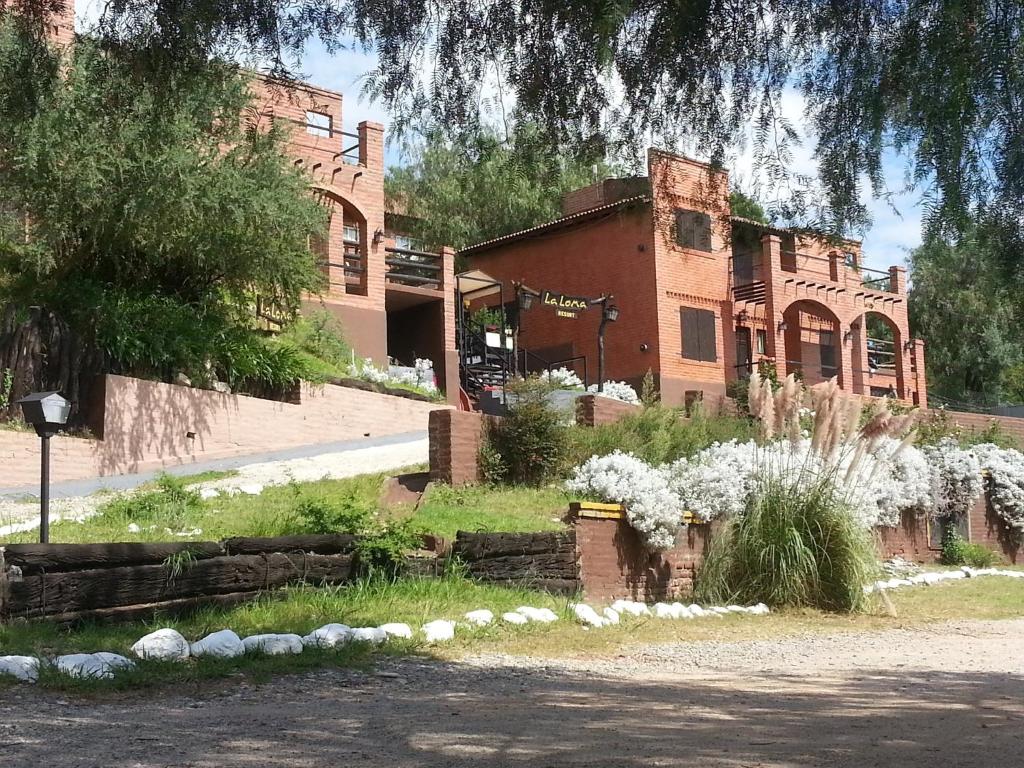 un gran edificio de ladrillo con flores blancas delante de él en La Loma Resort en Merlo