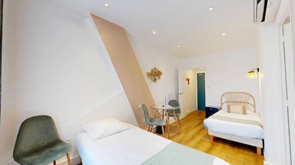 a small room with two beds and a chair at Hotel Solara in Nice