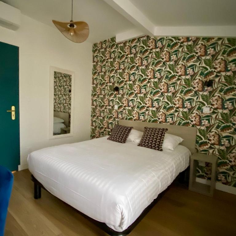 a bedroom with a large white bed with a wallpaper at Hotel Solara in Nice