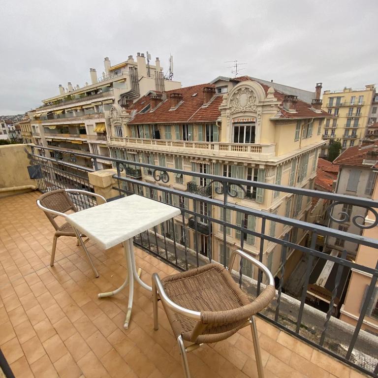 a table and chairs on a balcony with buildings at Hotel Solara in Nice
