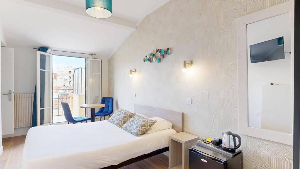 a small room with a bed and a table and chairs at Hotel Solara in Nice