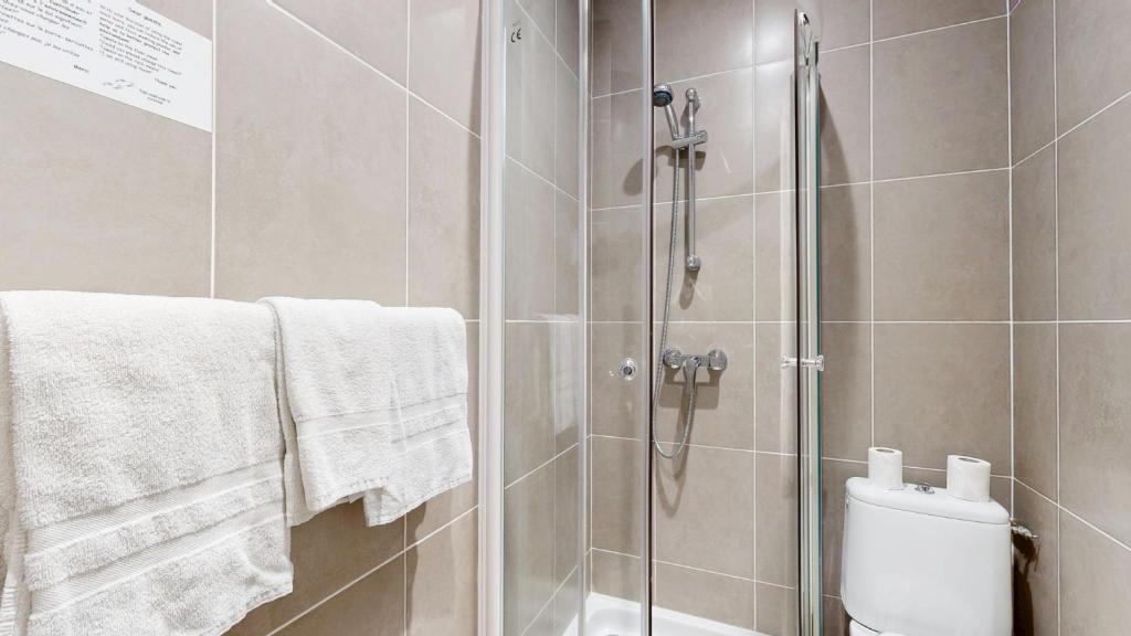 a bathroom with a shower and a toilet and towels at Hotel Solara in Nice