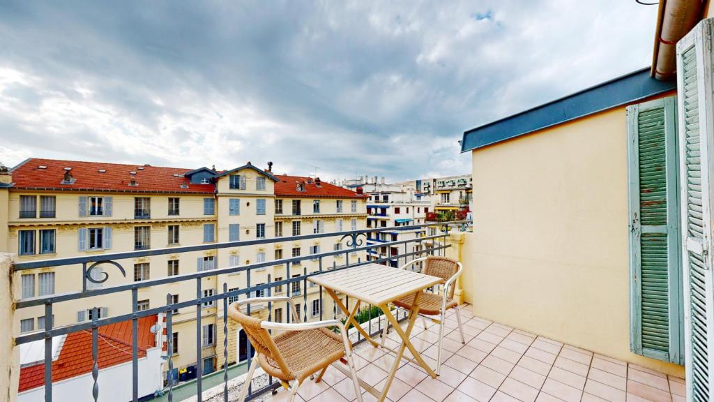 a table and chairs on a balcony with buildings at Hotel Solara in Nice