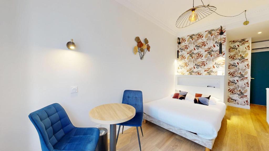 a room with a bed and a table and chairs at Hotel Solara in Nice