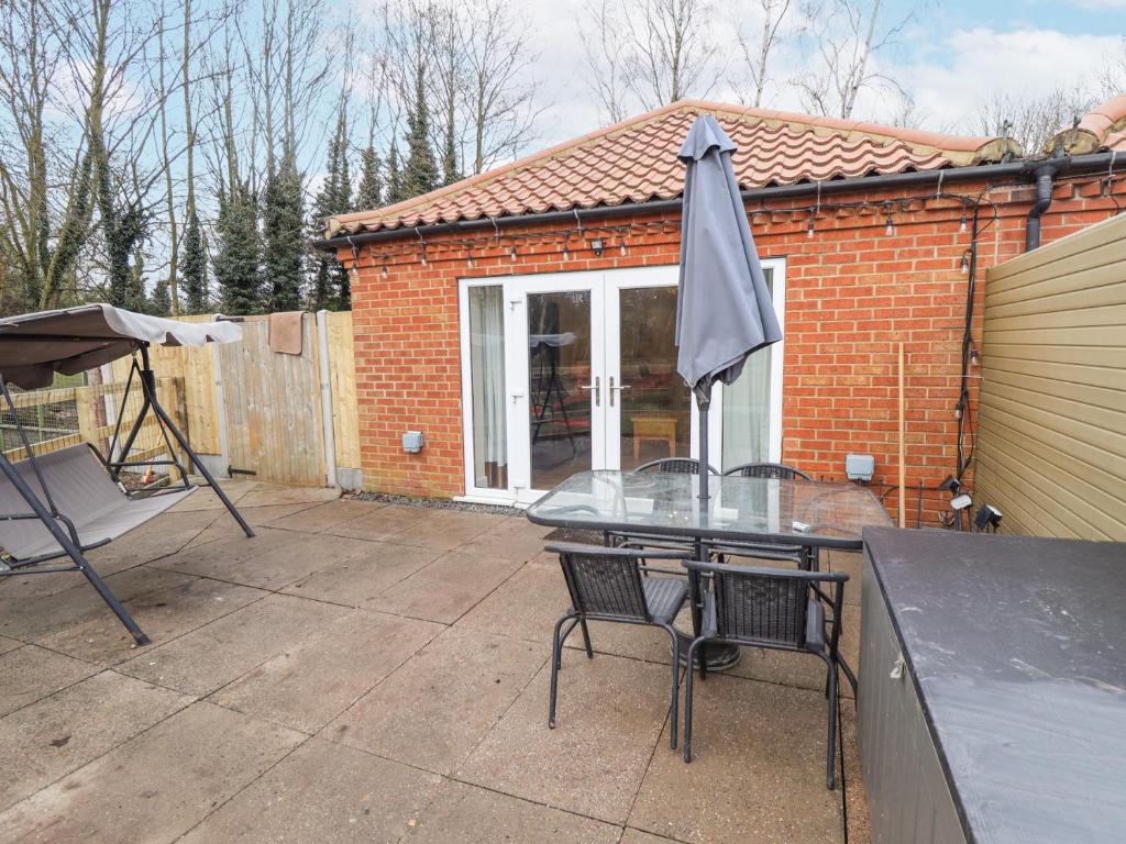 a patio with a glass table and an umbrella at Willow Cottage in Barrow upon Humber