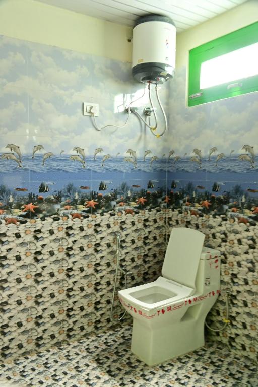 bagno con servizi igienici e un dipinto sul muro di Nomadic Den Manali a Manāli