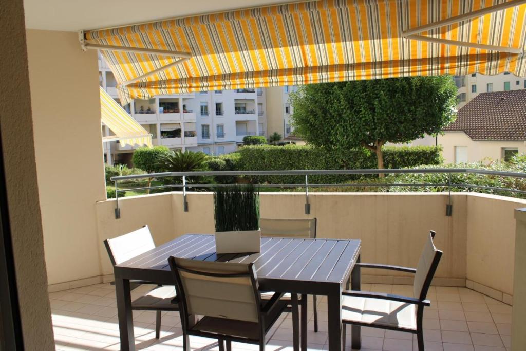 une table et des chaises sur un balcon avec un parasol dans l'établissement Espace republique, à Cannes