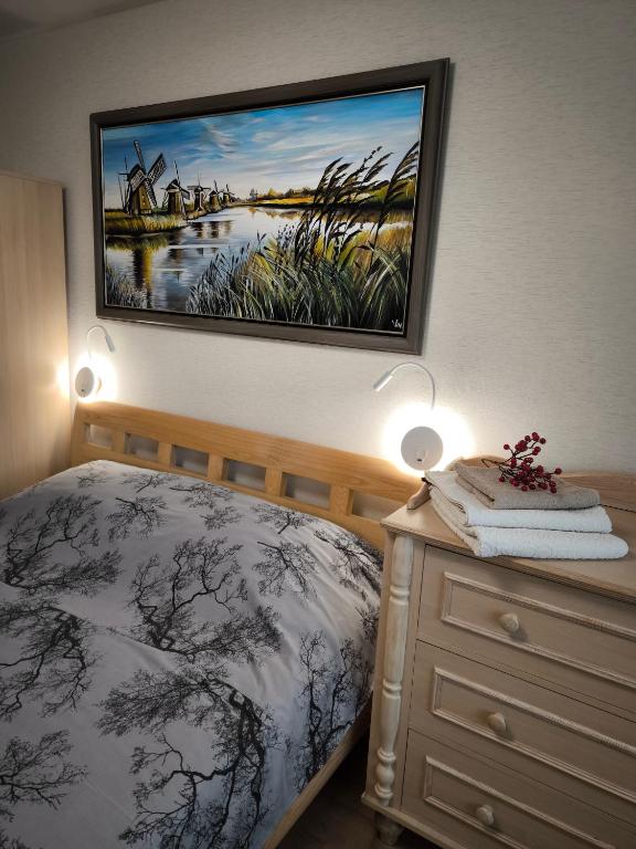 a bedroom with a bed and a painting on the wall at Debreceno apartamentai in Klaipėda