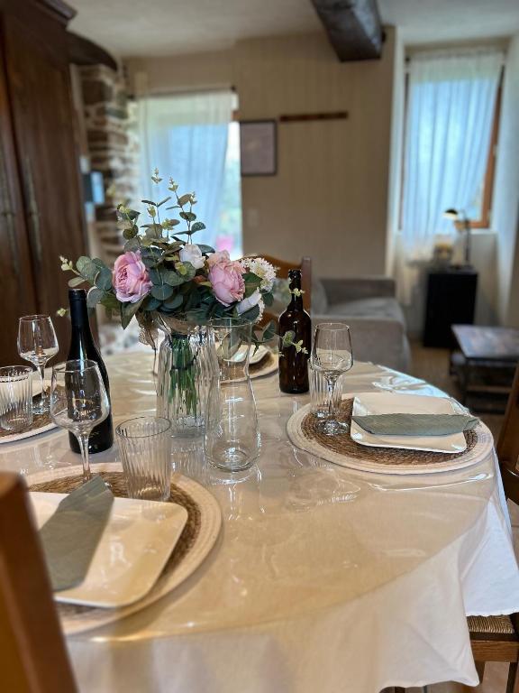 - une table avec un vase de fleurs et des bouteilles de vin dans l'établissement La maison de l'houblonnier vue mer, à Plurien