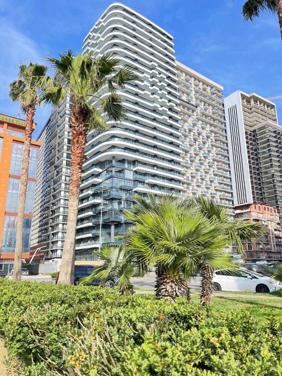 a tall building with palm trees in front of it at Sunny Spot Batumi in Batumi
