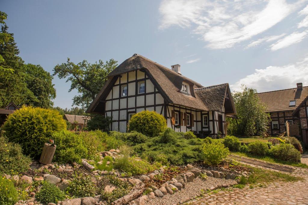 an old house with a thatched roof and a garden at Zagroda u Macieja in Ustka