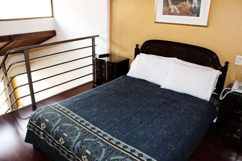 a bedroom with a bed with a blue blanket and white pillows at Suites Studio 40 in Bogotá