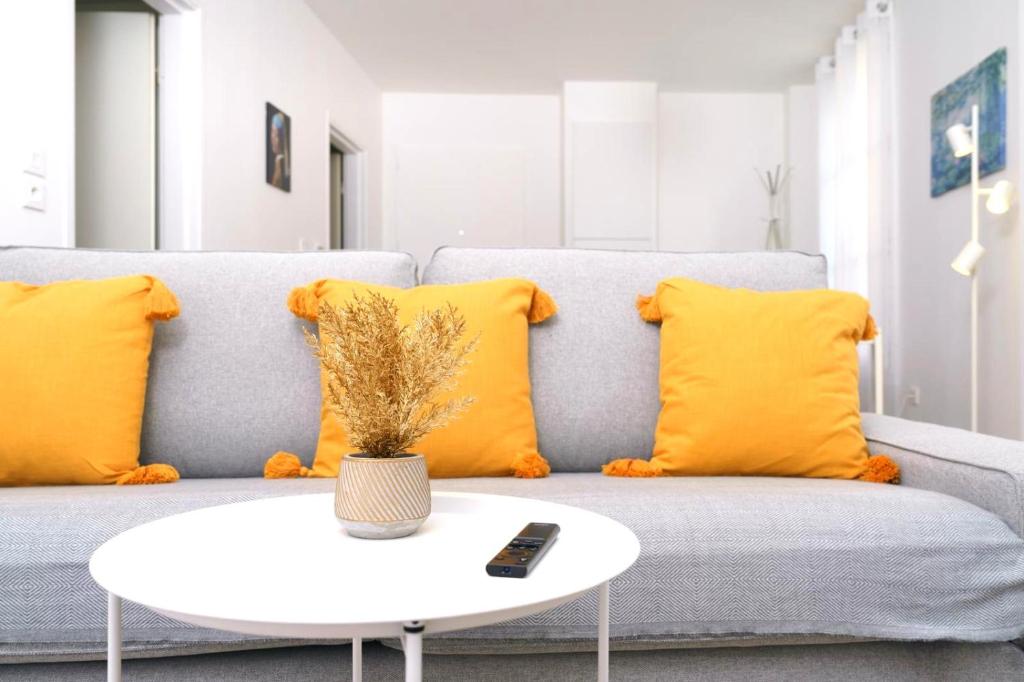 - un salon avec un canapé, des oreillers jaunes et une table dans l'établissement L'Escapade Montreuilloise, à Montreuil