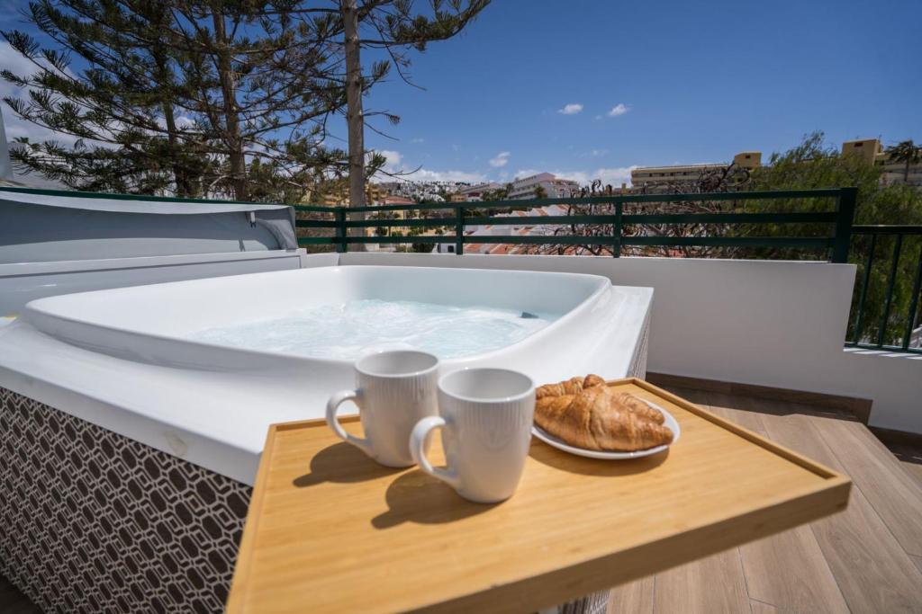 a hot tub with two cups and a plate of bread at Terrazza Luxury Costa Adeje in Adeje