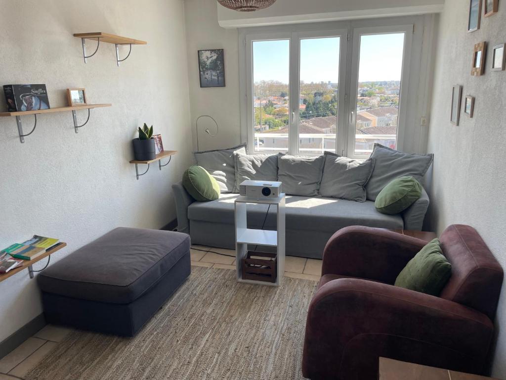 un salon avec un canapé et une fenêtre dans l'établissement Spacieux T4 tout confort, vue sur Bordeaux, à Mérignac