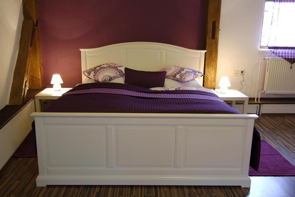 a white bed with purple sheets and pillows on it at Fontana Pizzeria - Pension in České Budějovice