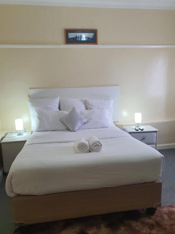 a bedroom with a large bed with two towels on it at Faranie Guesthouse in Oudtshoorn