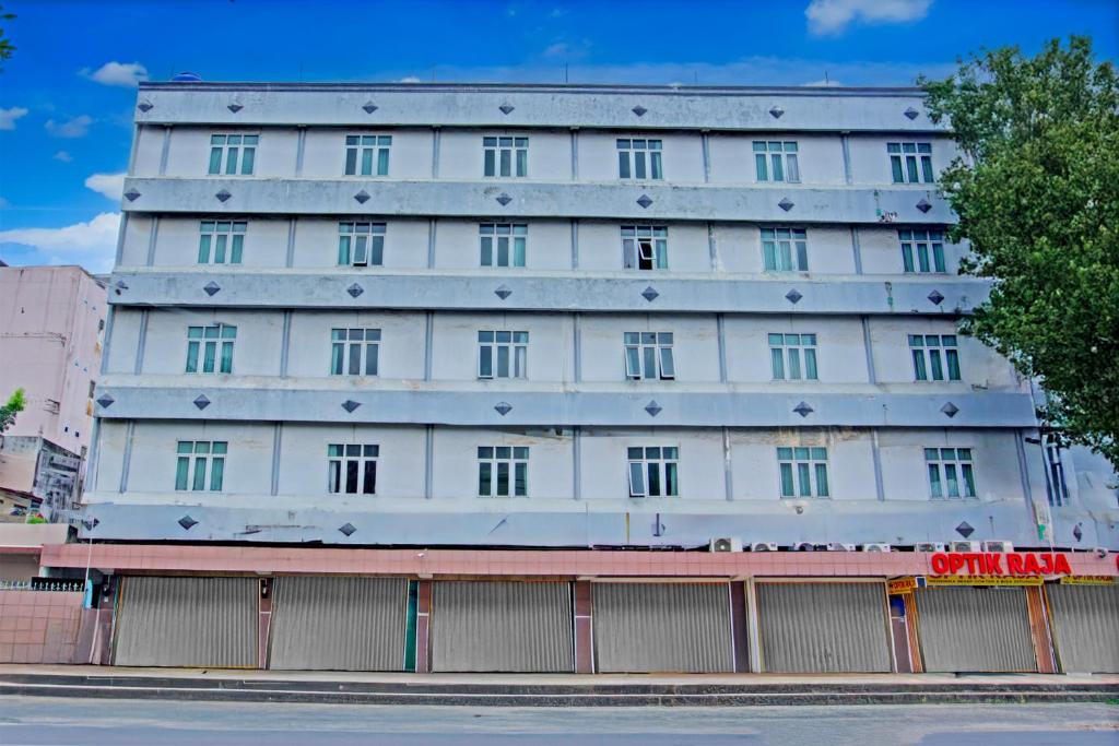 a white building with a fence in front of it at Townhouse Oak Palembang Near Jembatan Ampera Formerly Azzura Hotel in Palembang