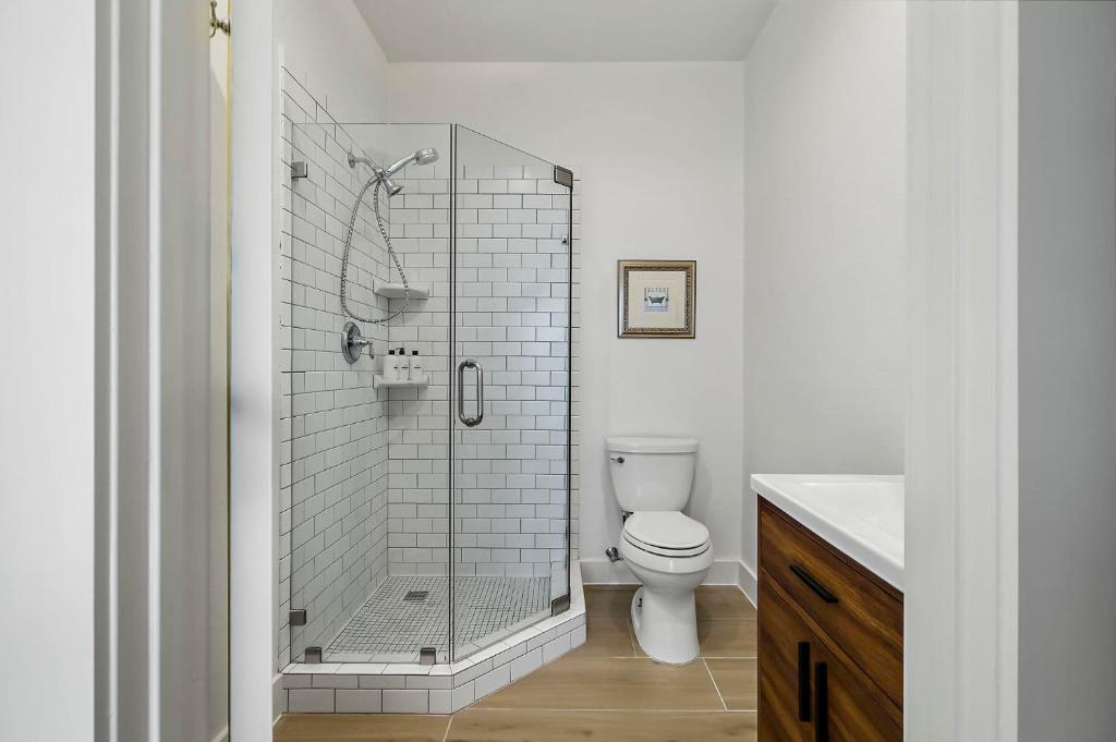 a white bathroom with a shower and a toilet at Lazy River Ranch - Lazy River Pool, Golf & Pickleball in Kreutzberg