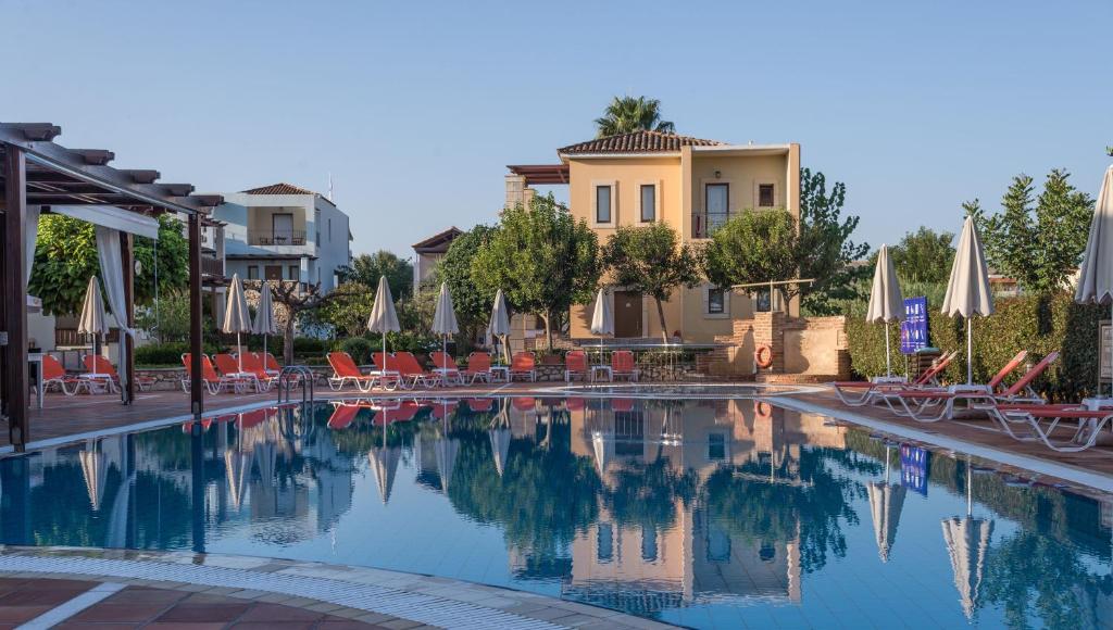 a swimming pool with chairs and umbrellas at Vagia Mare in Gerani