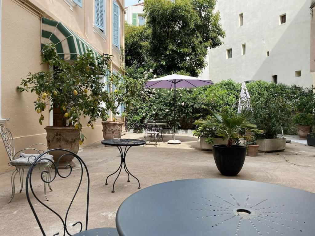 un patio avec une table, des chaises et un parasol dans l'établissement Cannes Studio - 12F, à Cannes