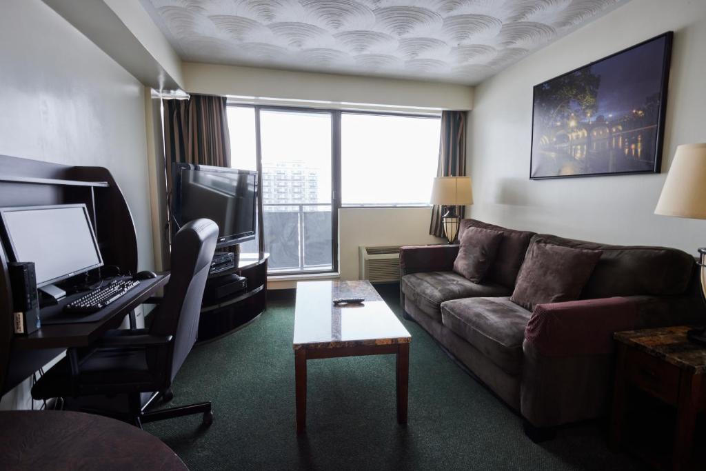 a living room with a couch and a desk with a computer at The Business Inn in Ottawa