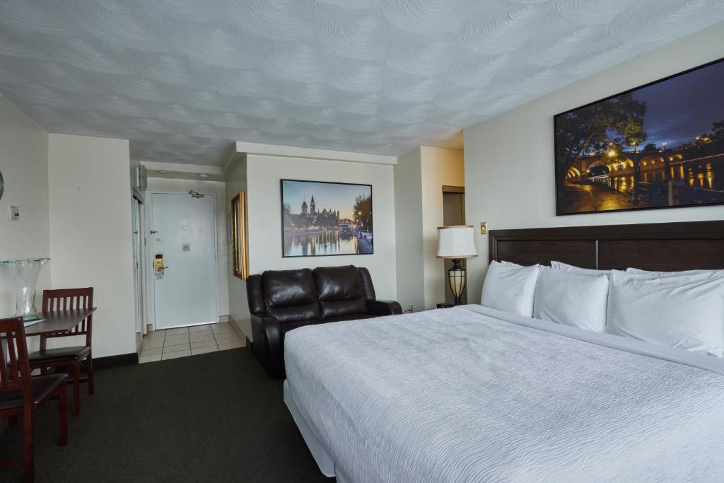 a hotel room with a bed and a chair at The Business Inn in Ottawa