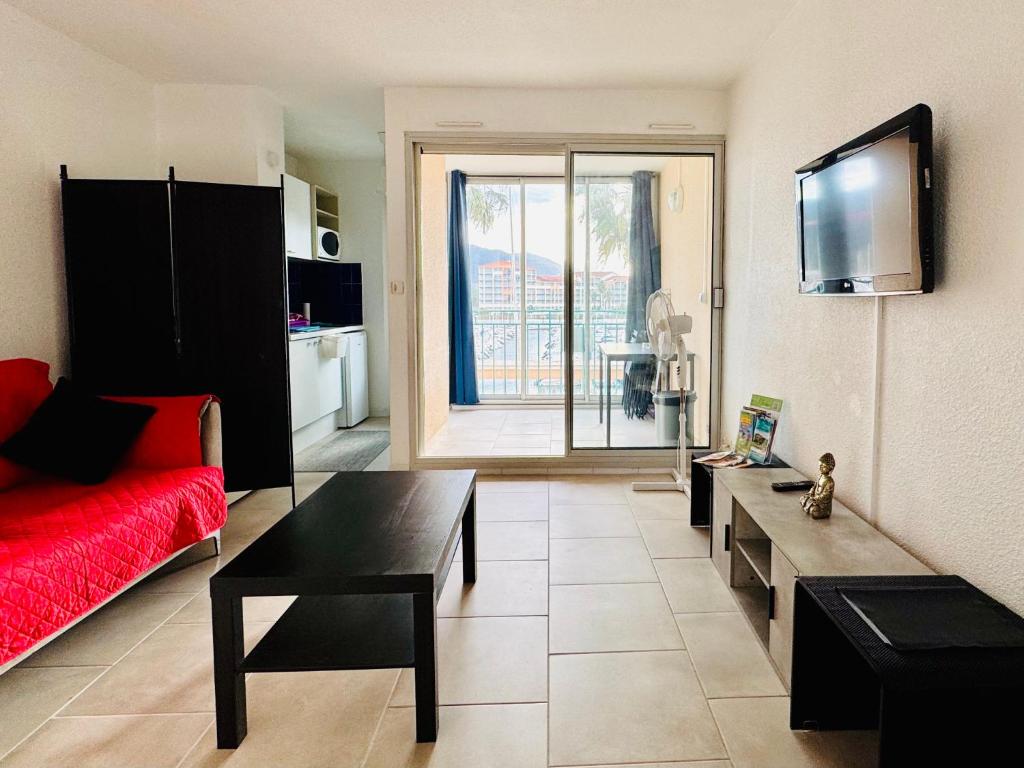 un salon avec un canapé rouge et une table dans l'établissement Le temps de vivre, à Plage dʼArgelès