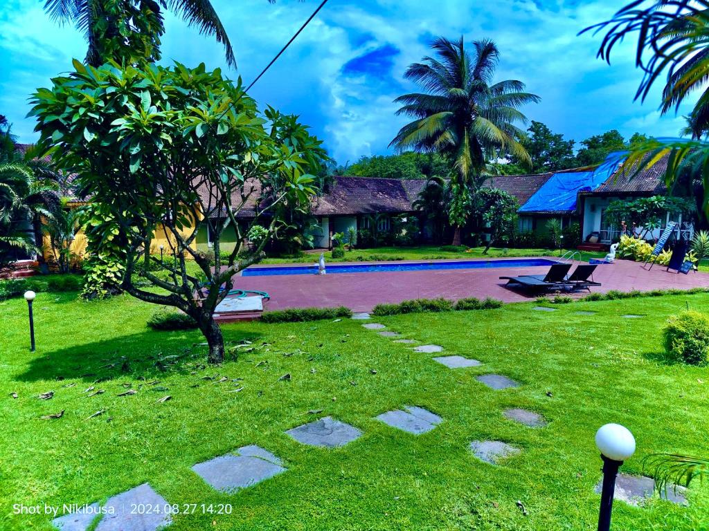 アンジュナにあるRashNik Villas & Reosrt Anjuna with pool & kitchenのスイミングプールと木があるリゾートヤード