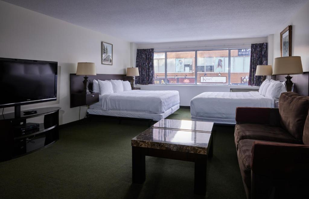 a hotel room with two beds and a flat screen tv at The Business Inn in Ottawa