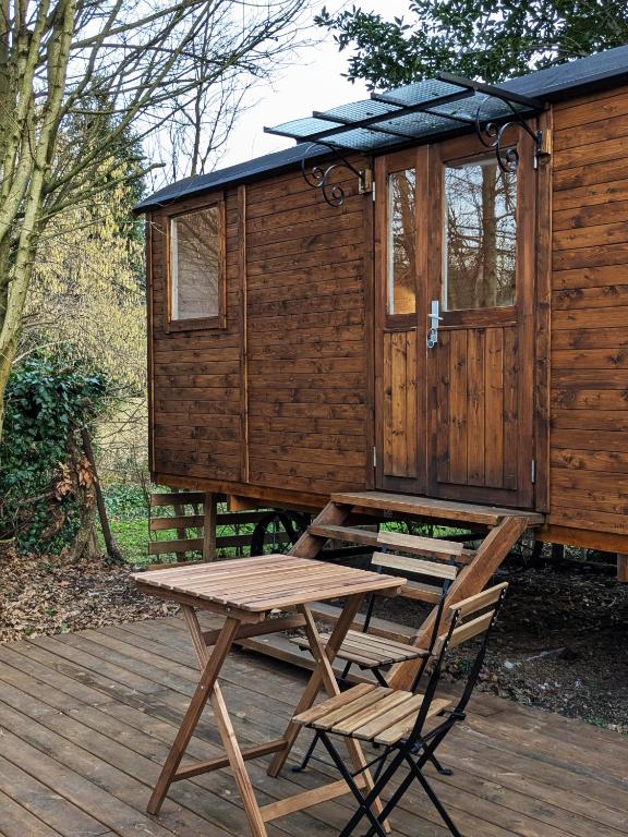 une table de pique-nique et une chaise sur une terrasse avec cabine dans l'établissement Roulotte avec terrasse à Montreuil, à Montreuil