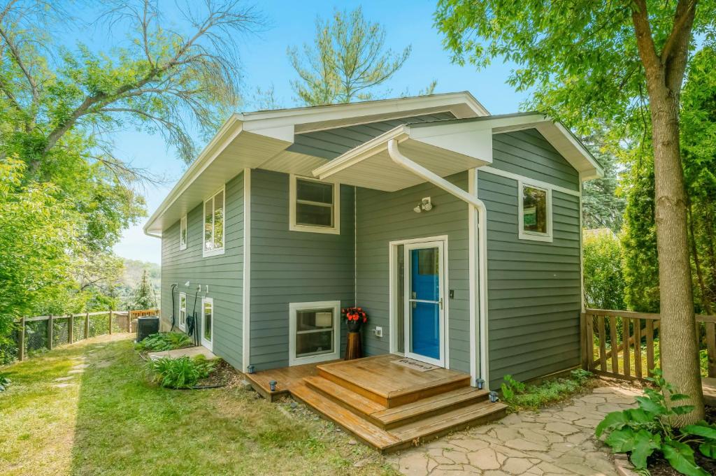 a green tiny house with a porch and stairs at Koselig Cottage on Medicine Lake in Minneapolis