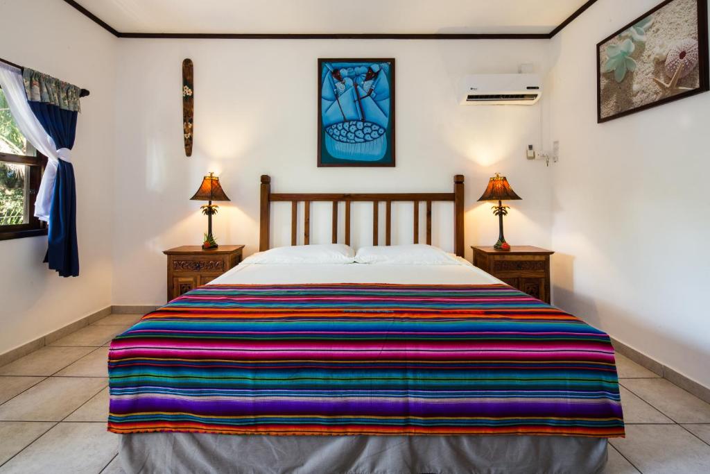 a bedroom with a bed with a colorful striped blanket at Splash Inn Dive Resort & Villas in West End
