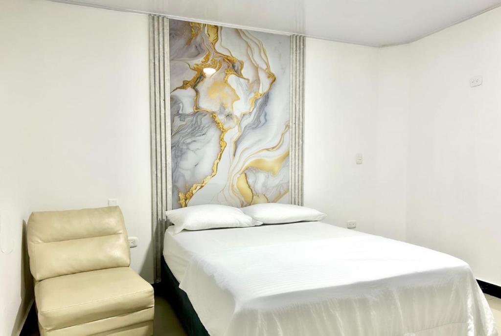 a bedroom with a white bed and a chair at Hotel Brisas Del Mar Suite in Santa Marta