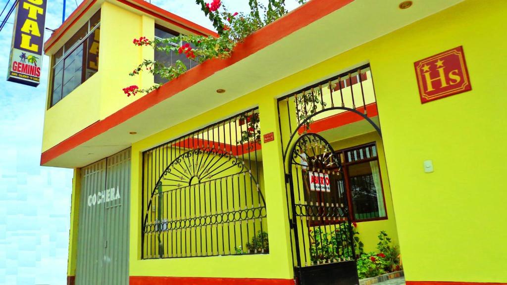 żółty budynek z bramami i kwiatami w obiekcie Hostal Geminis w mieście Ica