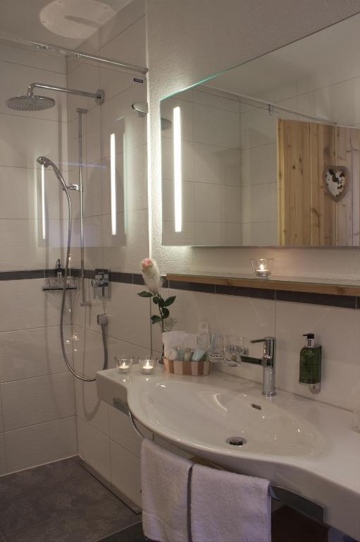 a bathroom with a sink and a shower with a mirror at Hotel Caprice - Grindelwald in Grindelwald
