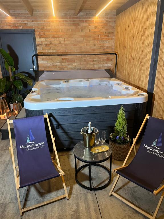a hot tub in a room with two chairs and a table at Karwia Marina Apartamenty in Karwia