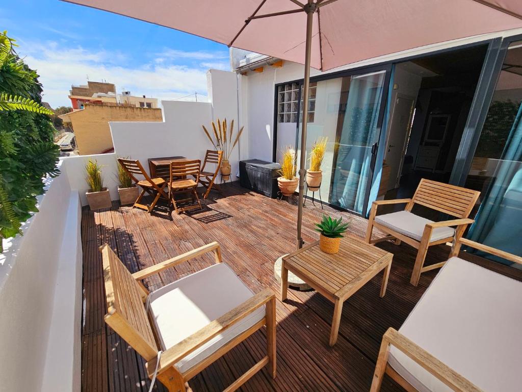 a deck with chairs and tables and an umbrella at Apartamentos de la Huerta in Alicante