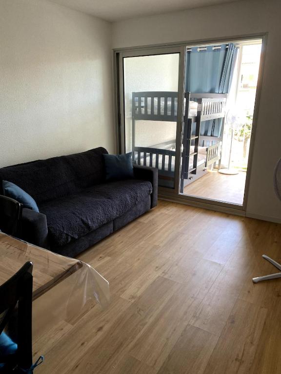 un salon avec un canapé et une porte coulissante en verre dans l'établissement Appartement neuf à 100m de la plage, à Marseillan