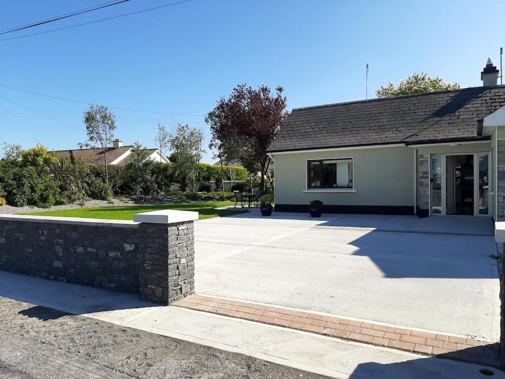 a house with a stone wall in front of a driveway at Watervalley Farm Self Catering in Cloongawn