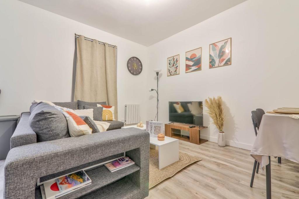 un salon avec un canapé gris et une table dans l'établissement La Pause Détente au pied du Stade de France, à Saint-Denis