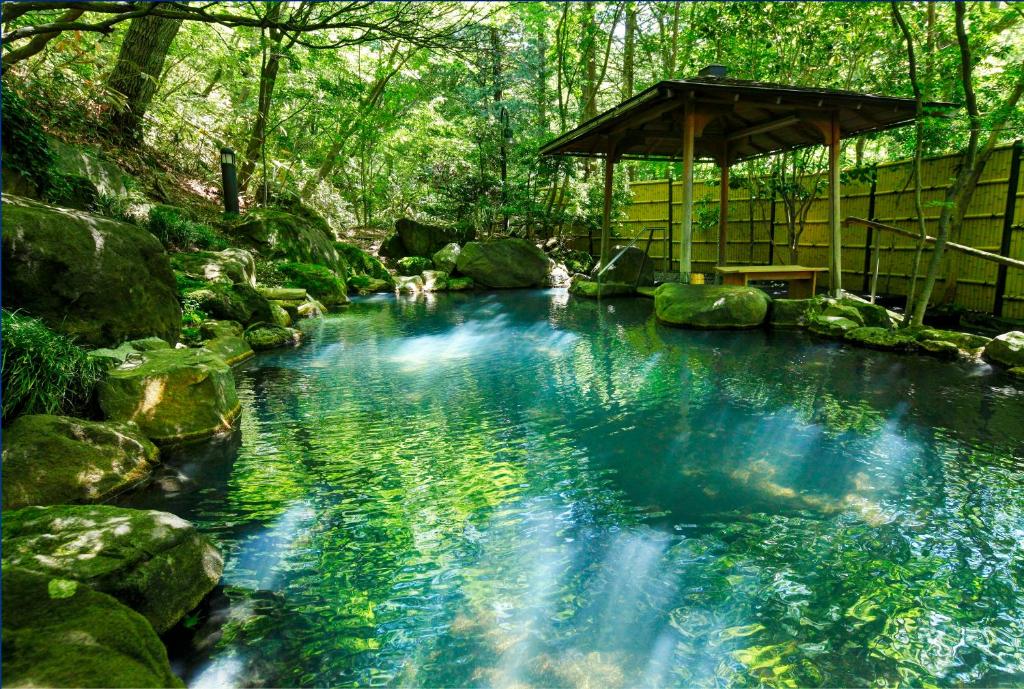 a pool of blue water with rocks and a gazebo at Nasu Onsen Sanraku in Nasu