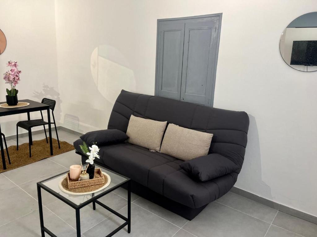 - un canapé noir dans le salon avec une table dans l'établissement JUST Cocooning, à Carpentras