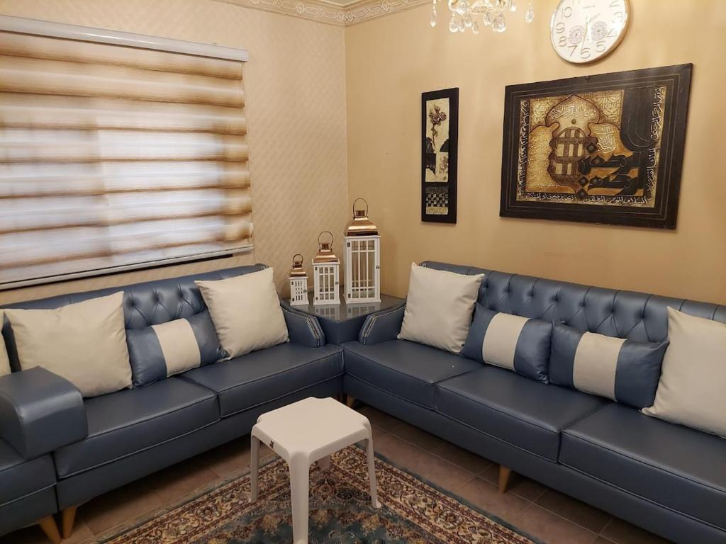 een woonkamer met een blauwe bank en een tafel bij Pool House at Janabiyah in Al Janabīyah