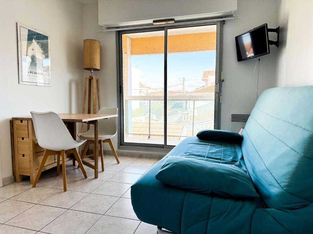un salon avec un canapé bleu et une table dans l'établissement Résidence La Croisette - Charmant T2 lumineux avec terrasse - Plage d’Eyrac MAE-9434, à Arcachon