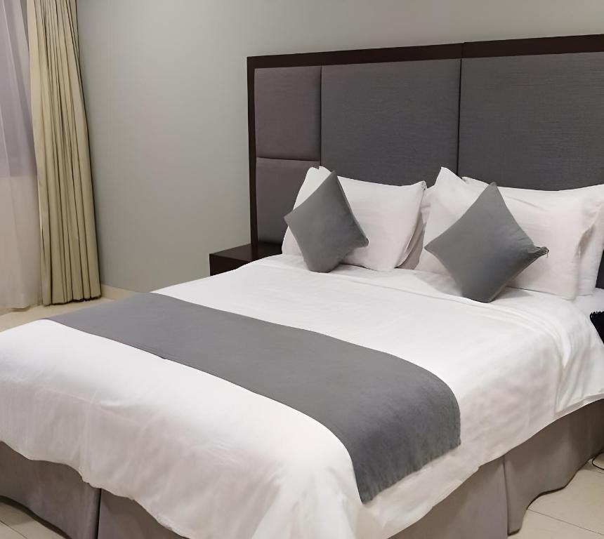 a bedroom with a large bed with white sheets and pillows at Abu Dhabi Center - For Elites in Abu Dhabi