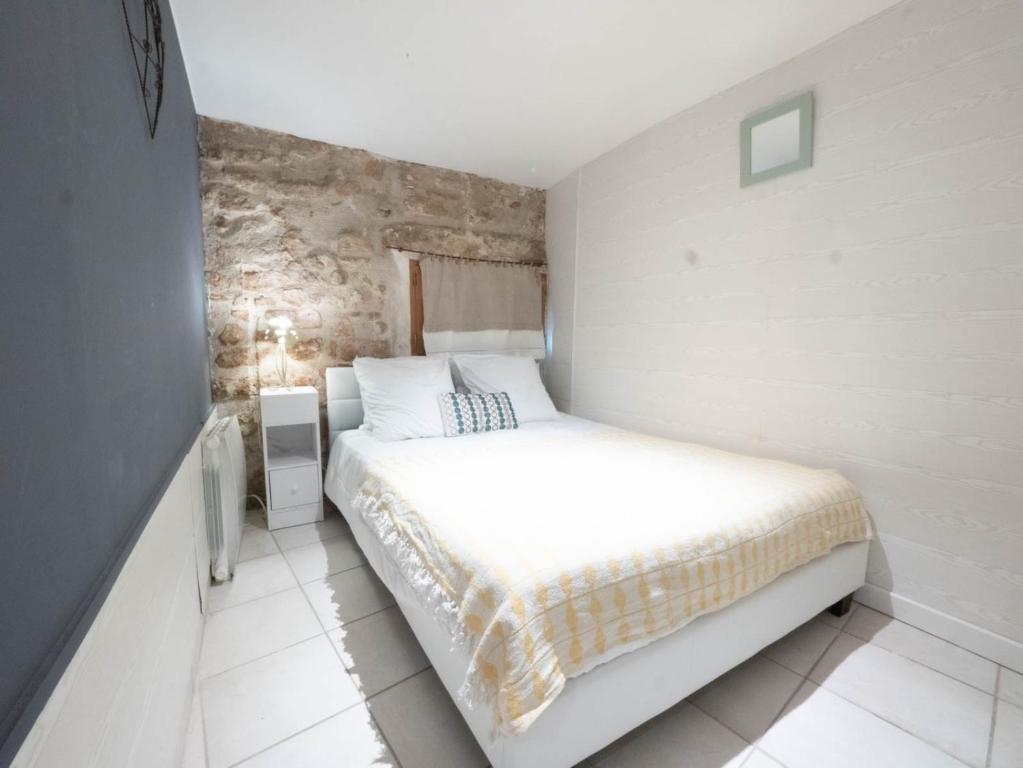 une chambre avec un lit blanc et un mur en pierre dans l'établissement L'Authentique - centre ville, à Montpellier