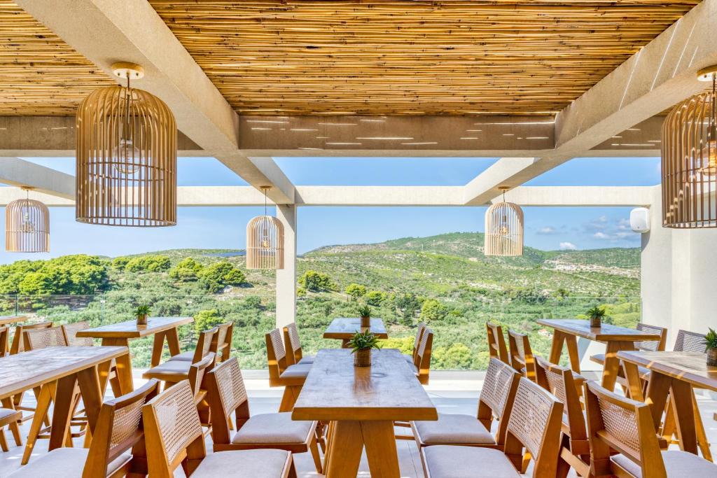 a restaurant with wooden tables and chairs and a large window at Myzith Luxury Suites in Keri
